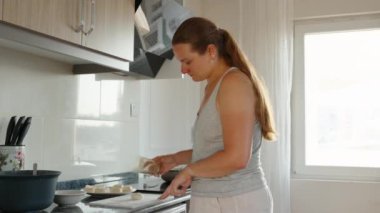 Yemek pişirmek. Ellerim ve bardağımla peynirli krep yapıyorum. Siyah tezgah. Beyaz tahta. Sarı cam. Hareket halinde.