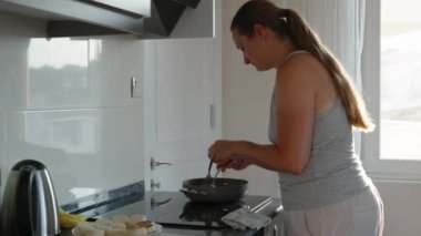 Yemek pişirmek. Peynirli krepleri tavadan çıkarıp bir tabağa koyuyorum. Pencerede güneş ışığı var. Hareket halinde.