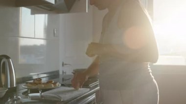Yemek pişirmek. Peynirli krepleri una sarıp kızartma tavasına koyuyorum. Siyah tezgah. Beyaz tahta. Pencerede güneş ışığı var. Hareket halinde.