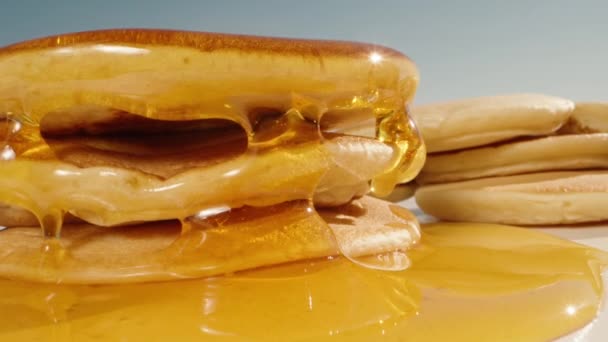 蜂蜜从一堆煎饼中排出 好吃的早餐蜂蜜在阳光下闪闪发光 多莉滑行极端特写 普罗伯慢动作 — 图库视频影像