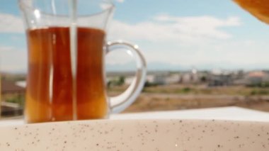 Krep kestim. Bal damlaları. Arkada bir fincan çay var. Yaz, mavi gökyüzü. Zengin kahvaltı. Dolly Slider aşırı yakın çekim. Laowa Sondası. Yavaş çekim.
