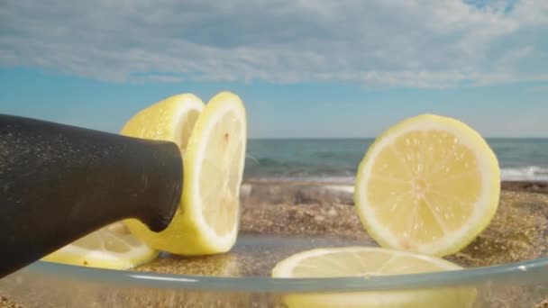 ナイフはレモンで立ち往生しました 海と雲の背景にプレート上のレモンのスライス ドリースライダー極端なクローズアップ — ストック動画
