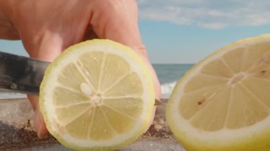 Bir tabakta limon kesiyorum, kamera yakınlaşıyor, yakın plan. Arka planda deniz var. Dolly kaydırıcı aşırı yakın çekim.