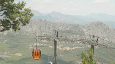 Kablolu araba, füniküler. Kırmızı teleferik halattan iniyor, halatlar halatta, destek direği. Dağ ve orman manzarası