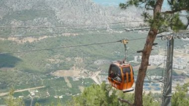 Teleferik, kırmızı füniküler, insanları aşağı ve dağa çıkarır. Arkasında şehir ve orman olan deniz..