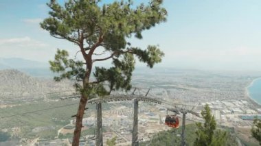 Teleferik, kırmızı füniküler, insanları aşağı ve dağa çıkarır. Arkasında şehir ve orman olan deniz..