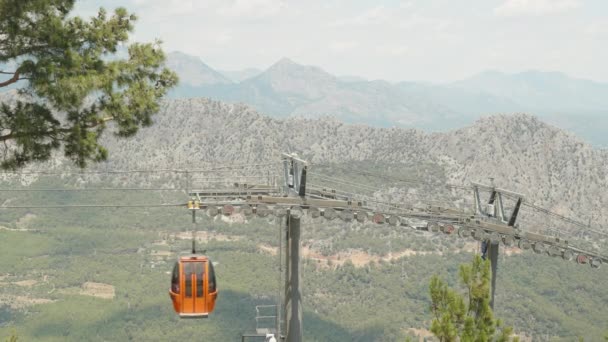 滑稽的 红色的缆车沿着缆绳滑行 滚轮在缆绳上 支撑杆 山区和森林观点 — 图库视频影像