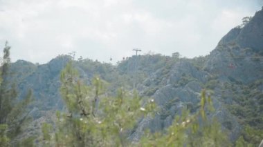 Kablolu araba, kırmızı funicular insanları taşır. Ağaçların arasından aşağıdan bak.