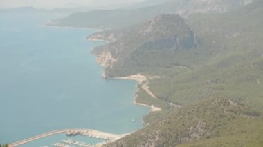 Dağdan denize kadar manzarayı ve limana park etmiş yatları, çalıların arasından pembe çiçeklerle..