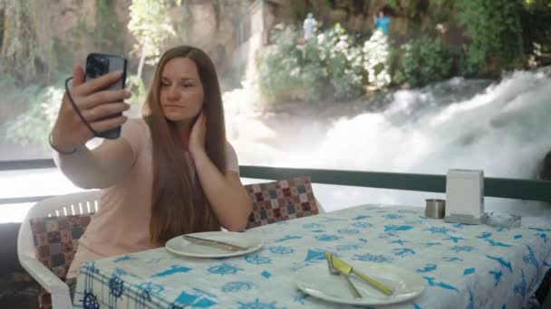 Una Joven Sentada Café Agua Toma Una Selfie Contra Telón — Vídeos de Stock