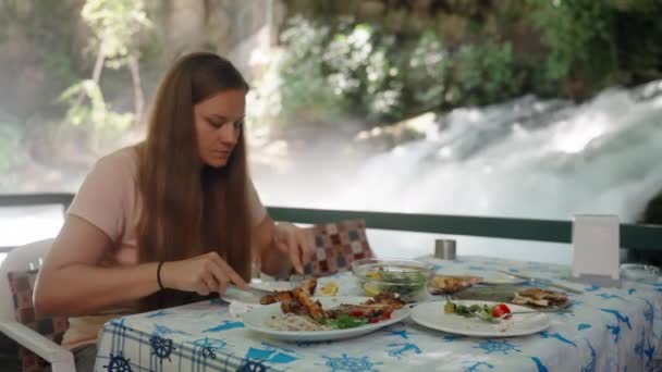 Jonge Vrouw Zit Een Café Het Water Snijdt Kebab Eet — Stockvideo