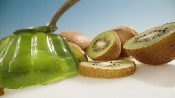 Green Jelly Kiwi Pieces Hit Spoon Shakes Background Blue Sky — Stock Video