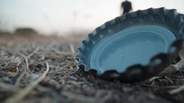 Kız parkta yerde yatan metal bir şişe kapağını kaldırdı. Yakın plan, doğada çöp toplama