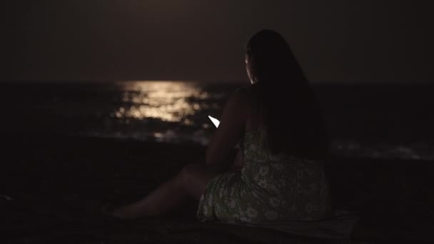Młoda Kobieta Sukience Siedzi Nad Morzem Plaży Zagląda Smartfona Światło — Wideo stockowe