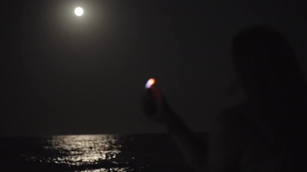 Tânără Stă Lângă Mare Plajă Luminează Brichetă Lumina Lunii Apă — Videoclip de stoc