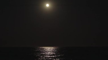 Büyük bir dolunay okyanusu aydınlatır. Dalgalar, suda ışık.