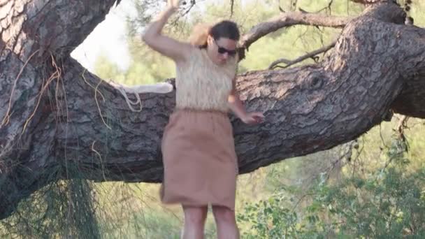 一个穿着裙子的年轻女子从松树上跳了下来 落日在森林里 — 图库视频影像