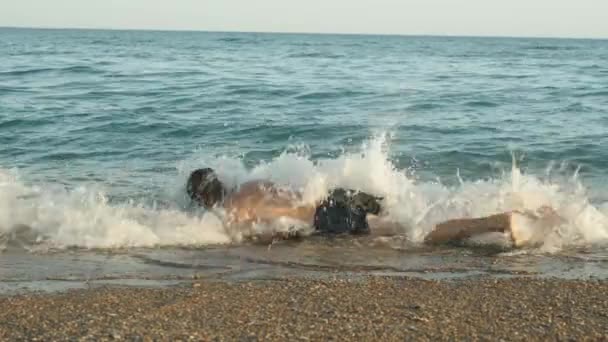 スキューバダイビングのマスクの男は海岸に沿って水の中に転がり 波に覆われています スローモ — ストック動画