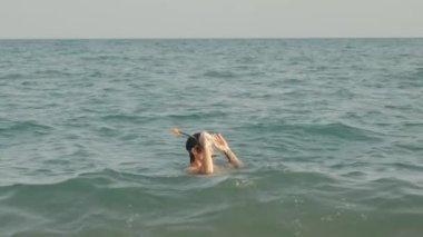 Bir adam denizin derinliklerinden bir maske ve tüp içinde çıkar ve ağzından bir lolipop çıkarır. Maskesini çıkarır ve sırtüstü yatar..