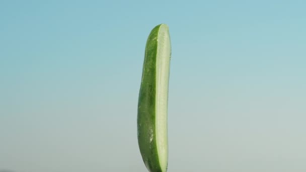 半绿色的黄瓜在蓝天的背景下在特写下旋转 — 图库视频影像