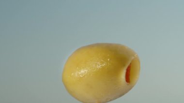 Kırmızı bir zeytin içinde yeşil bir zeytin, yakın plan mavi gökyüzü üzerinde döner.