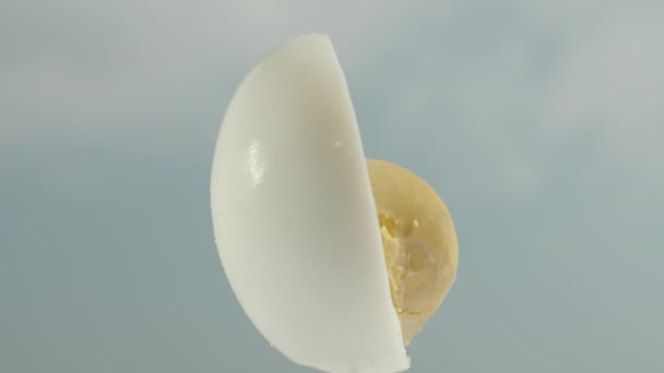 半分にカットされたゆで卵は クローズアップで青い空の背景に回転します — ストック動画