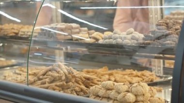 Dükkandaki şekerleme ve ekmek reyonunda, eldivenli satıcı tohumlu ekmek çubukları koyar..