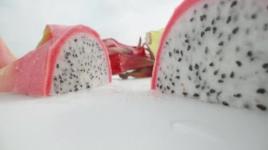 Pitahaya ya da beyaz etli ejderha meyvesi, ikiye bölünmüş. Beyaz bir masada. Dolly Slider aşırı yakın çekim. Laowa Sondası