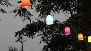 Dışarıda ağaçlara bağlanmış renkli fenerlerle dolu bir çelenk..