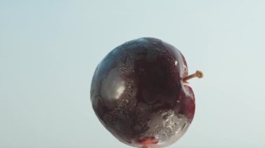 Mavi gökyüzünde dönen kırmızı eriğin yarısı, yakın plan..