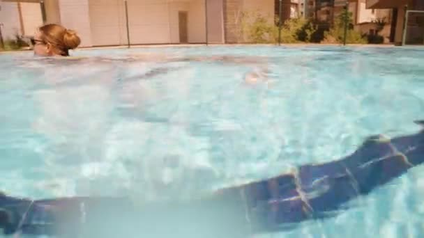 游泳池和水下相机 一个穿着黄色泳衣的年轻女子在游泳 摄像机跟在她后面走到水底 — 图库视频影像