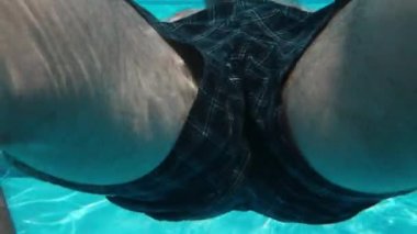 Yüzme havuzu ve su altında kamera. Kıllı erkek bacakları, havuzun duvarından itiyor. Yavaş çekim