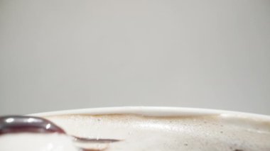 Kahve fincanının içine çikolatalı şekerlemeler döküldü. Kamera içinden geçiyor. Beyaz arka plan. Dolly kaydırıcı aşırı yakın çekim.