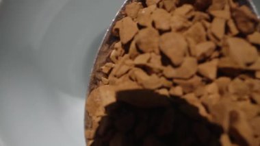 Hazır kahveyi bir kaşıktan beyaz bardağa dolduruyorum, ağır çekimde. Dolly kaydırıcı aşırı yakın çekim.