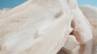 Dilimlenmiş şampiyonları beyaz bir masaya serpiştirirken, kamera mavi gökyüzüne doğru onların arasından geçer. Dolly sürgülü çok yakın plan. Dolly kaydırıcı aşırı yakın çekim.