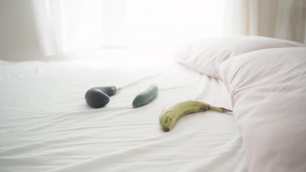 床上有茄子 黄瓜和香蕉 这是一个阳光灿烂的早晨 窗外的光线落在白色的床上 风吹着窗帘 多莉滑翔机特写 — 图库视频影像