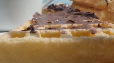 Kamera içinden geçerken Viyana waffle 'ına bıçakla çikolata sürüyorum. Masada bir kupa var..