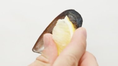 Açık bir midye beyaz bir arkaplanda dönüyor, limon sıkıyorum.
