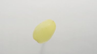 Yalnız bir yeşil üzüm beyaz bir arkaplanda döner, yakın plan