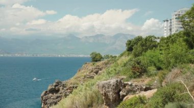 Deniz manzarası, dağlar ve şehir yüksek bir uçurumdan. Suda bir tekne.