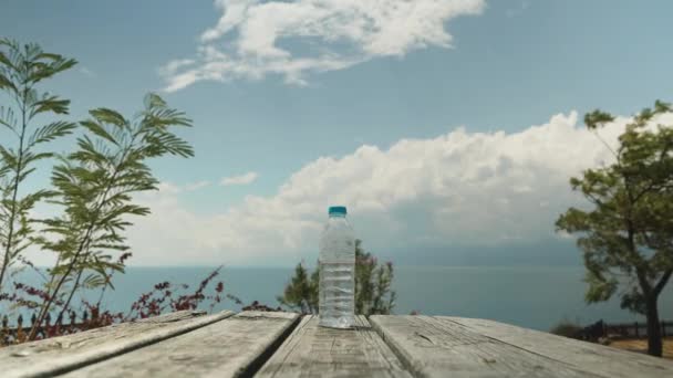 Egy Üveg Víz Egy Asztalon Kilátás Tengerre Felhőkre Fákra — Stock videók