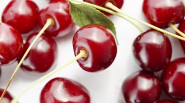 Beyaz arka planda kiraz çilekleri, ortada dönüyor. Makro