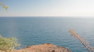 Denizin kıyısındaki bir uçurumun kenarında dikiliyordu. Mavi su ve gökyüzü.