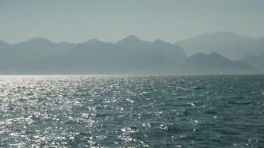 Güneşli bir günde deniz, uzakta dağlar, suda hafif bir sis. Panorama