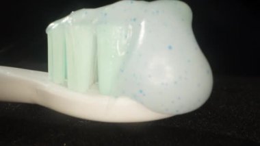 Beyaz, mavi noktalı diş macunu siyah arka planda, aşırı yakın plan..