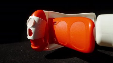 Kırmızı sprey şişedeki deterjan, siyah arka planda duruyor. Dolly kaydırıcı aşırı yakın çekim.