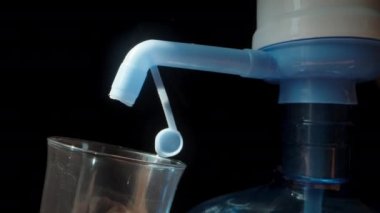 Büyük bir şişe su ve musluğu olan bir pompa, bir bardağa su dökerim, kamera su akıntısının içinden geçer. Dolly kaydırıcı aşırı yakın çekim.