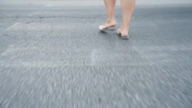 Genç bir kadın karşıya geçiyor, bacakları yakın, fayanslar yolda..