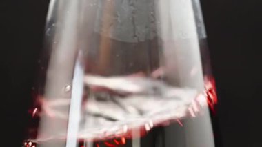 Siyah arka planda bir kadeh kırmızı şarap, şarabı sallarım. Kapat.