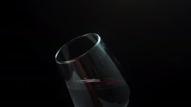 Kırmızı şarabı bardakta sallayıp kokluyorum, yakın plan. Siyah bir arka planda. Yavaş çekim